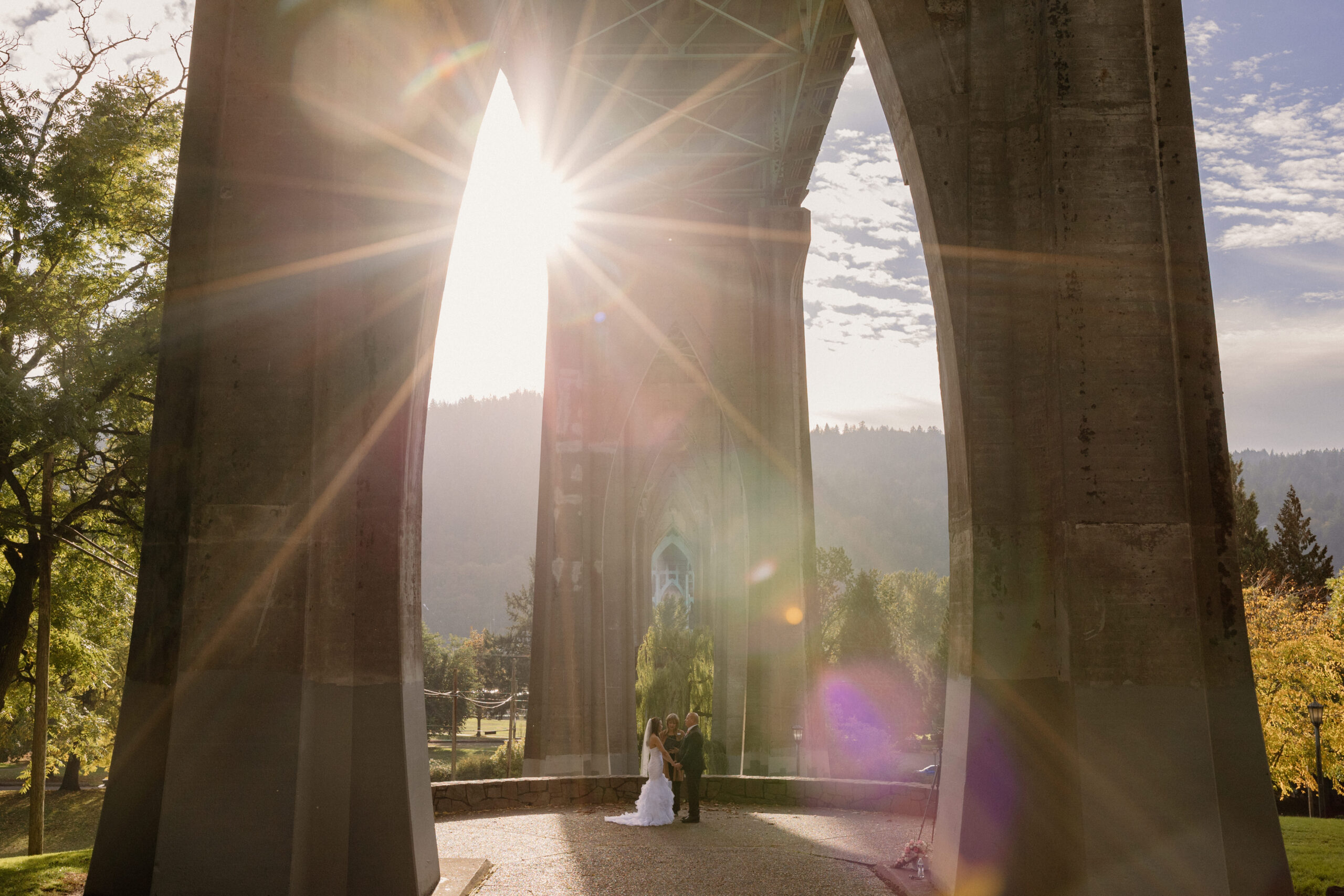 A gorgeous sunset peeking through the St Johns Bridge during a Cathedral Park elopement ceremony.