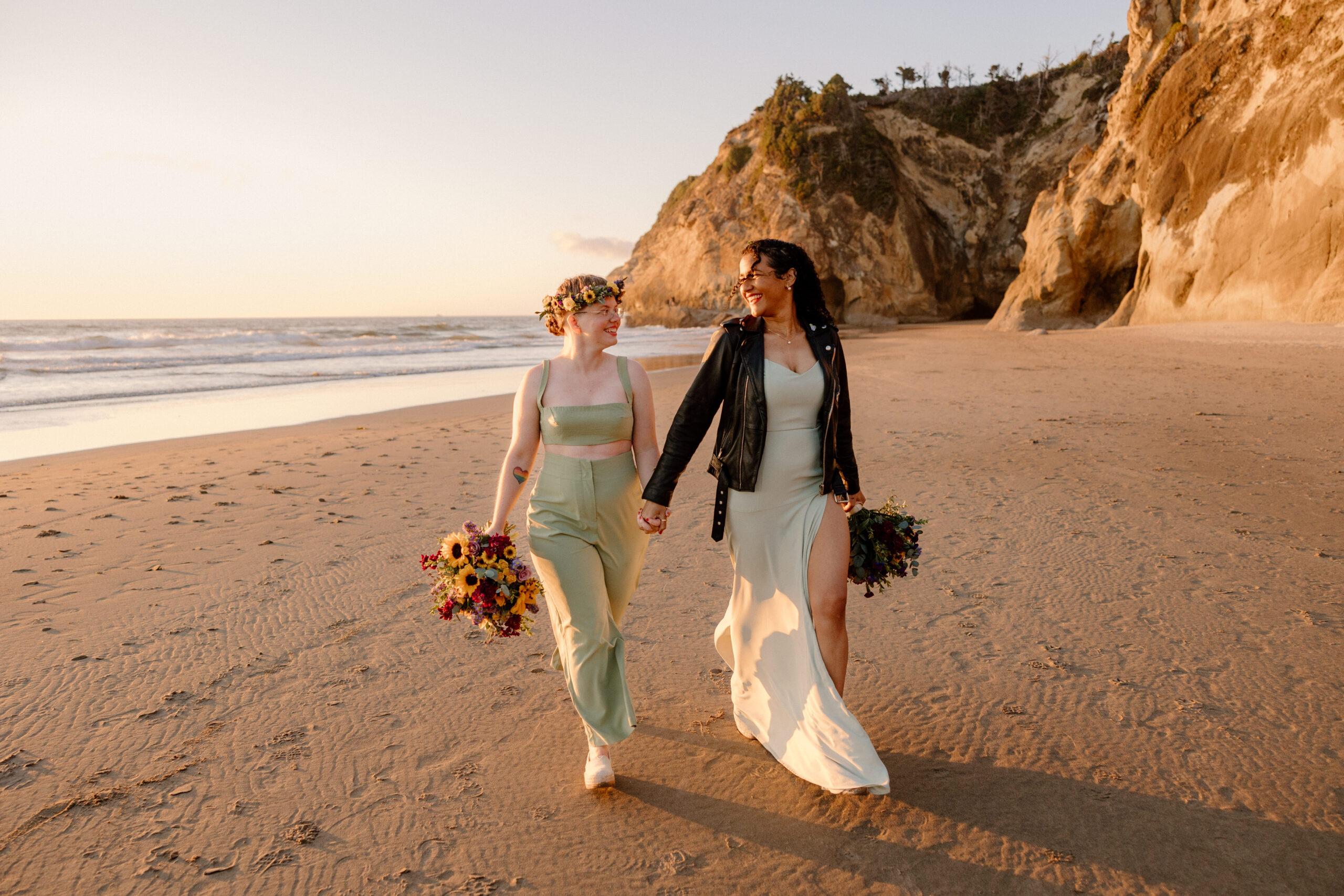 Two brides run along the beach taking sunset photos at their Hug Point elopement ceremony at the Oregon Coast.