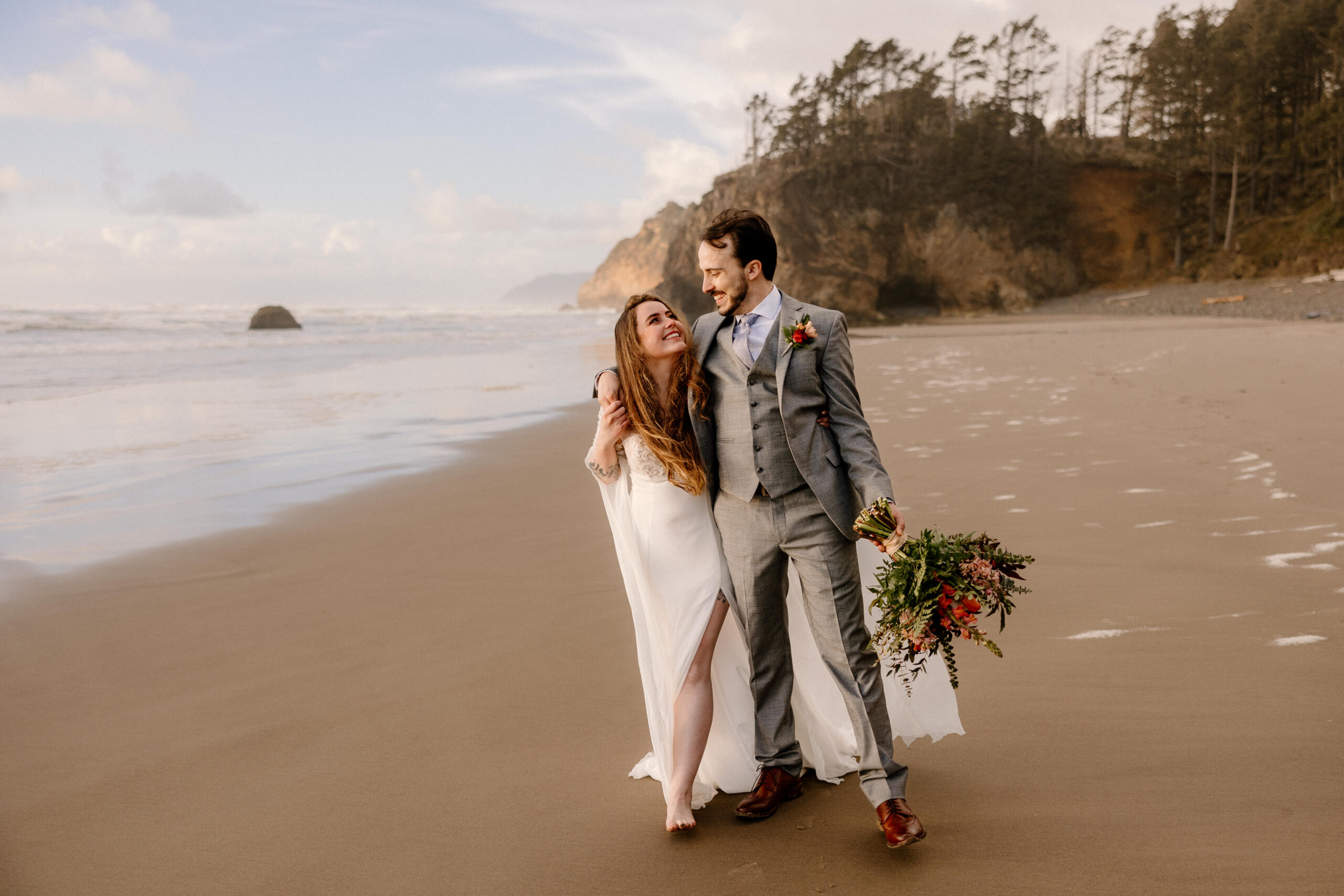 A couple walks along the beach at Hug Point on the Oregon Coast after their elopement ceremony.