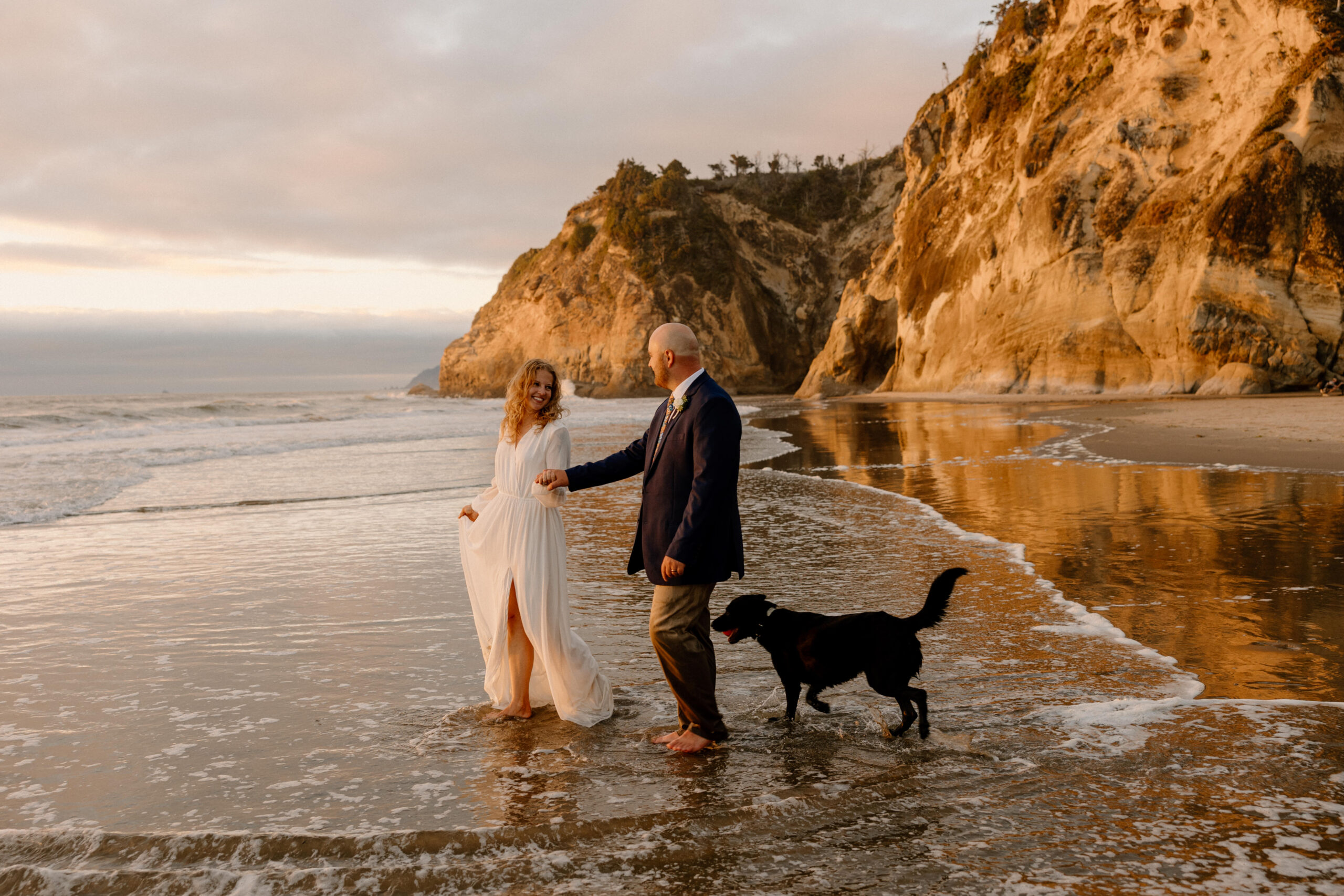 an elopement couple walking on Hug Point beach in Oregon at sunset.